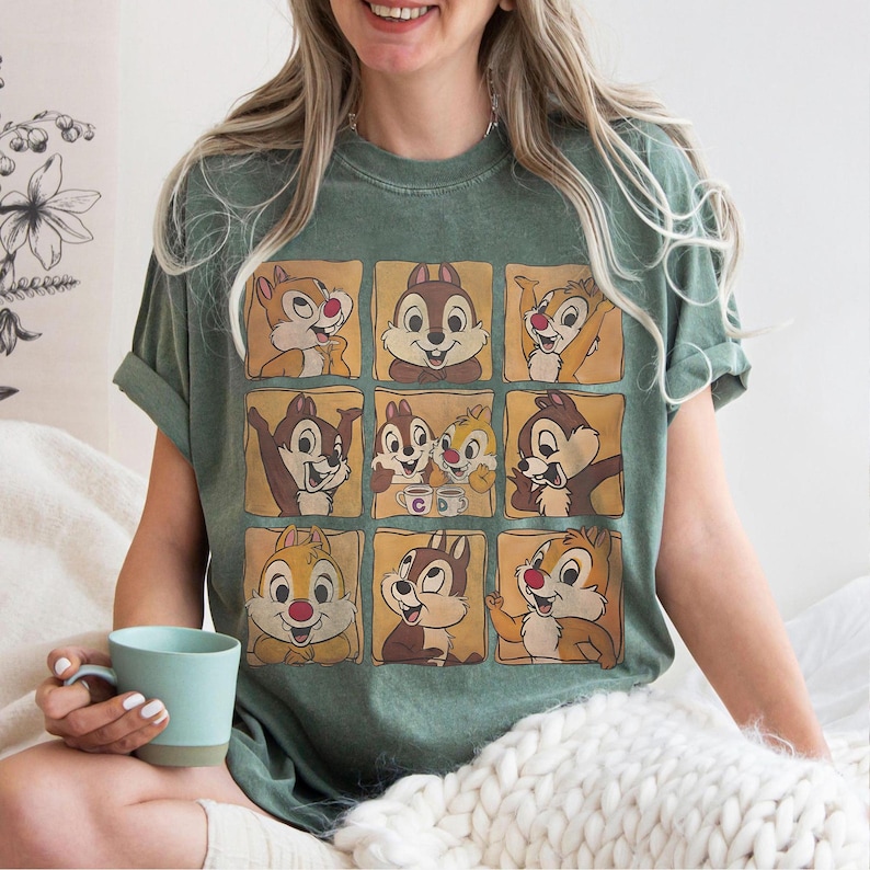 May include: Green t-shirt featuring a grid of cartoon chipmunks in various poses. The chipmunks have brown and tan fur, red noses, and are set against a light brown background. The shirt is a relaxed fit.