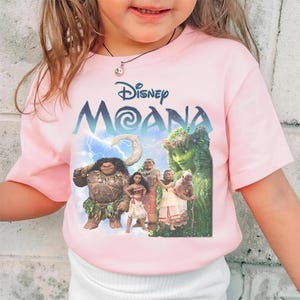 Pu&ograve; includere: Maglietta rosa con il design del film Disney "Moana". La maglietta presenta il titolo del film in blu e bianco, insieme alle immagini dei personaggi, tra cui Maui e Moana, su uno sfondo di cielo nuvoloso. Abbigliamento per bambini.