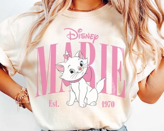 May include: Cream-colored sweatshirt featuring the Disney character Marie, a white kitten with a pink bow. The word "MARIE" is in pink block letters, with "Disney" above and "Est. 1970" below.