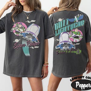May include: A charcoal gray short-sleeve t-shirt featuring Buzz Lightyear graphics. The front displays Buzz Lightyear, a spaceship, and the text Space Ranger. The back shows Buzz Lightyear, a spaceship, and the text Buzz Lightyear To Infinity & Beyond.