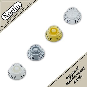 May include: Four circular guitar control knobs arranged diagonally, featuring numbers zero through ten in black. The set includes one clear, one yellow, one silver, and one white knob, each with a ridged side and a central mounting hole.