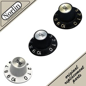 May include: Three guitar tone control knobs. Two are black with white numbers and a silver top that says "TONE". The third is white with black numbers and a silver top that says "TONE". The image also includes the text "original replacement parts".