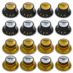 May include: A collection of guitar knobs in various styles. Some are black with gold or silver text and markings, while others are gold-colored with black text. The knobs are labeled "VOLUME" and "TONE" with number markings.