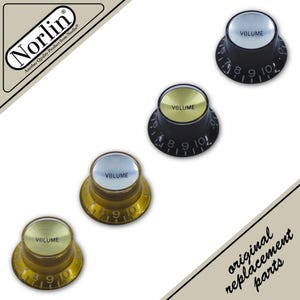 May include: Four circular volume control knobs for musical instruments. Two knobs are black with silver tops, and two are translucent amber with gold tops. Each knob features the word VOLUME and numbered markings from 0 to 10. Norlin branding is visible.
