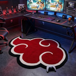 Puede incluir: Una configuración de juego con una silla ergonómica negra y roja, un escritorio con múltiples monitores y una alfombra roja en forma de nube con detalles blancos. La habitación está decorada con figuras y carteles de anime.