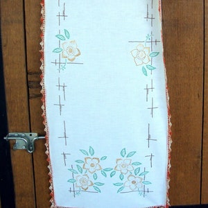 Camino de mesa de lino con bufanda y bordado de flores doradas y hojas verdes con borde de crochet en tonos naranjas abigarrados