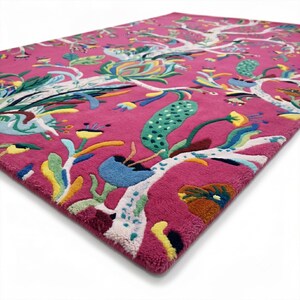 May include: A rectangular area rug featuring a vibrant magenta background with a multi-coloured botanical pattern. The design includes white tree-like branches, stylised flowers, and leaves in shades of blue, green, yellow, and orange.