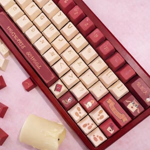 May include: A red and cream-colored mechanical keyboard with custom keycaps. The keycaps feature themed icons and text, including "Hogwarts School" and "Magic". The keyboard has a red frame and a unique layout.