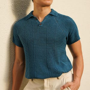 Puede incluir: Un polo de color verde azulado con un patrón texturizado y cuello abotonado se combina con pantalones color crema. La persona lleva gafas de sol negras. El conjunto es informal pero elegante.