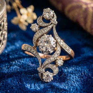 May include: A gold ring featuring a large central round-cut diamond surrounded by a swirling, elongated metal frame encrusted with smaller pavé-set diamonds. The design includes additional round-cut diamonds at the top and bottom terminals.