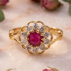 Peut inclure: Une bague en or avec une pierre précieuse centrale ronde d'un rose profond, entourée d'un halo de dix petites pierres claires rondes. Le sertissage présente un cadre métallique festonné et l'anneau se divise en deux bras fins et polis.