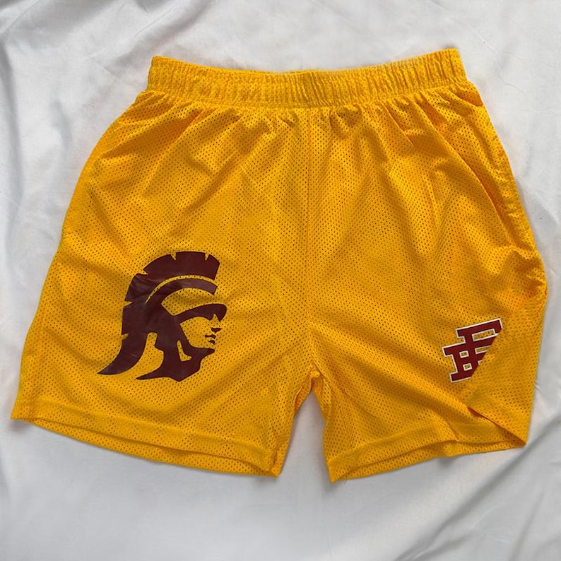 May include: Yellow mesh shorts featuring a maroon gladiator helmet graphic on the left leg and a maroon letter graphic on the right leg. The shorts have an elasticated waistband.