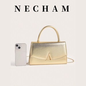 May include: A gold-colored handbag with a top handle and a chain strap. The bag has a rectangular shape with a flap closure and a gold-colored metal accent in the shape of a triangle. A smartphone is next to the bag. The word "NECHAM" is at the top.