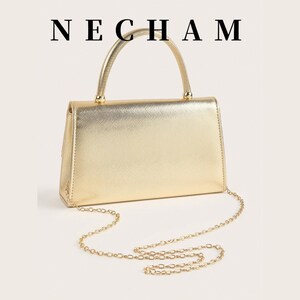 May include: A gold-colored handbag with a top handle and a chain strap. The rectangular bag has a metallic finish and the brand name "NECHAM" is printed at the top.
