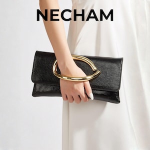 Peut inclure: Pochette noire avec une poignée dorée. La pochette est rectangulaire avec une surface texturée et un rabat. La poignée dorée est une grande forme incurvée. Le mot "NECHAM" est imprimé en noir en haut.
