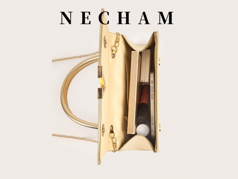 May include: A gold-colored handbag with a top handle and chain strap, open to reveal contents. The bag contains a smartphone, makeup, and other accessories. The word "NECHAM" is printed at the top.