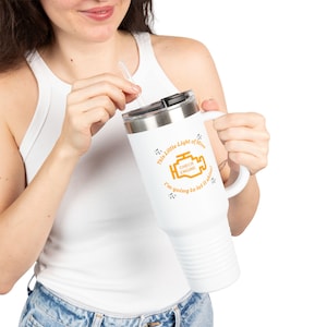 May include: White travel mug with a black lid and handle. The mug features the text "This Little Light of Mine, I'm going to let it shine!" and a graphic of a check engine light in orange.