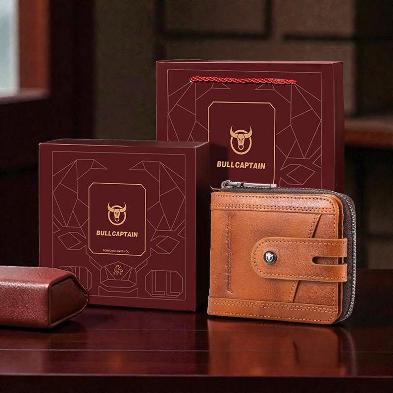 May include: A brown leather wallet with a zipper closure and a snap closure, displayed with two maroon gift boxes. The boxes feature the "BullCaptain" logo and a bull head emblem. The wallet is a bi-fold style.