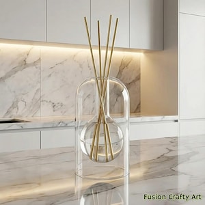 May include: A clear glass diffuser with a spherical interior and a dome-shaped cover. Gold-colored reeds extend upwards from the sphere. The diffuser sits on a marble countertop. The text "Fusion Crafty Art" is visible in the bottom right corner.