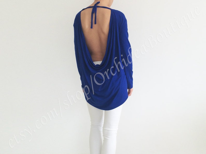 May include: A royal blue long-sleeved top with a low back and a draped design. The top is made of a soft, stretchy fabric.
