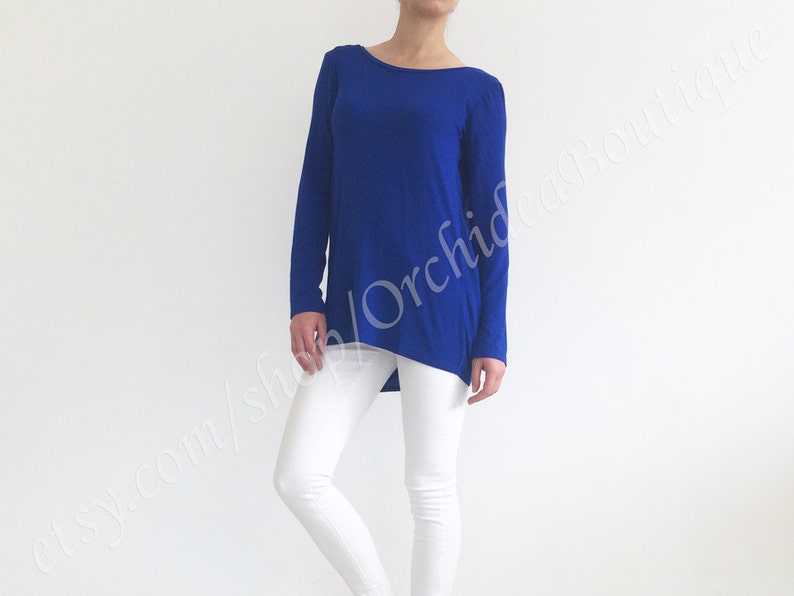 May include: A royal blue long-sleeved shirt with a high, round neckline. The shirt is made of a soft, stretchy fabric and has a slightly asymmetrical hemline.