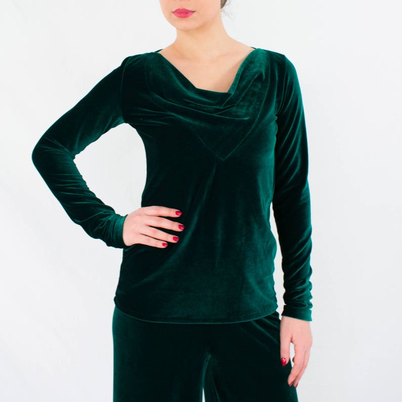 May include: A long-sleeved, emerald green velvet top with a cowl neck and a relaxed fit.