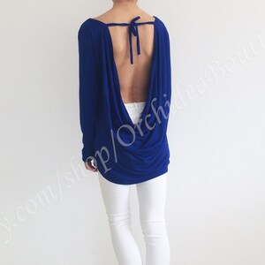 May include: A royal blue long-sleeved top with a low back and a tie at the neck. The top is made of a soft, stretchy fabric and has a relaxed fit.
