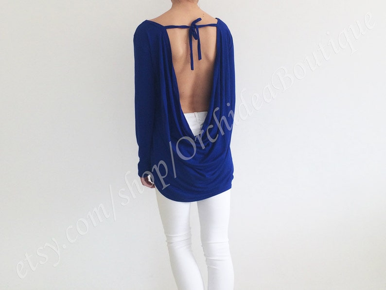 May include: A royal blue long-sleeved top with a low back and a tie at the neck. The top is made of a soft, stretchy fabric and has a relaxed fit.
