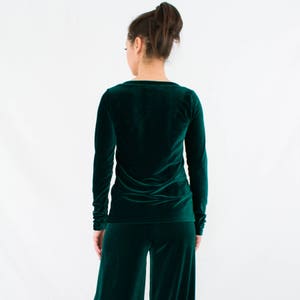 May include: A long-sleeved, emerald green velvet top with a scoop neck and a fitted silhouette.