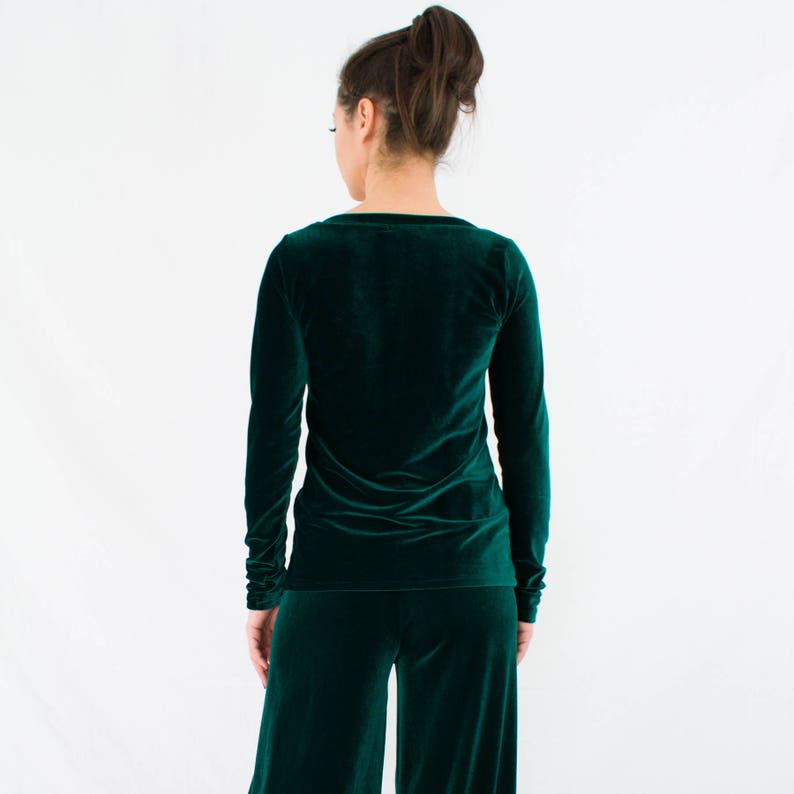 May include: A long-sleeved, emerald green velvet top with a scoop neck and a fitted silhouette.