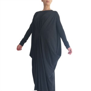 May include: A long, loose-fitting, charcoal gray dress with long sleeves and a gathered detail at the front.