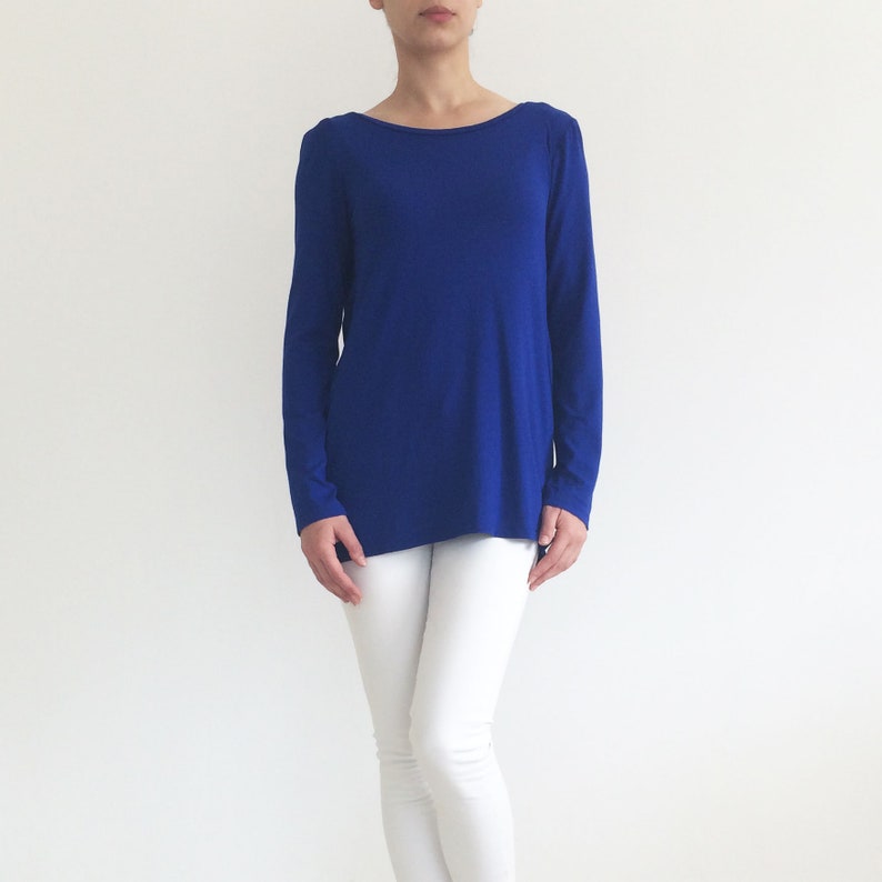 May include: A royal blue long-sleeved shirt with a scoop neck and a slightly longer back hem.