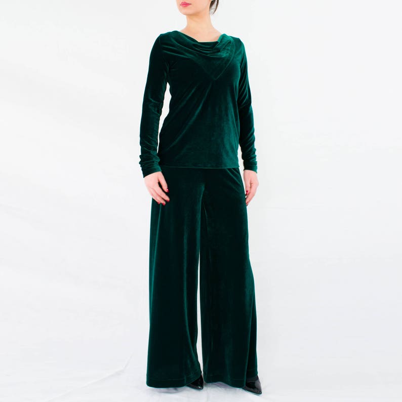 May include: A dark green velvet pantsuit with a cowl neck top and wide-leg pants.