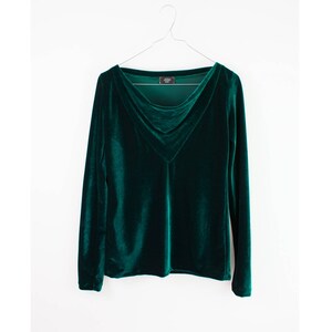 May include: A dark green velvet long-sleeved shirt with a V-neck and a draped neckline.
