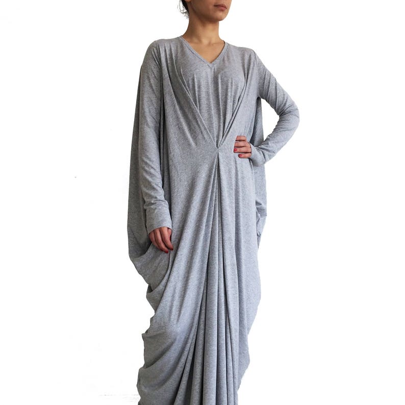 May include: A long, gray, loose-fitting dress with a V-neck and long sleeves. The dress is made of a soft, stretchy fabric and has a flowing, relaxed fit.