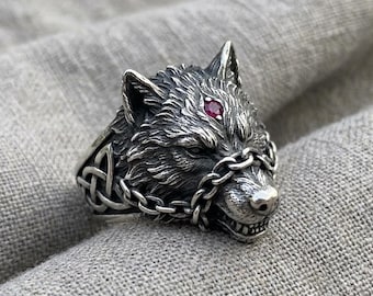 Anillo con cabeza de lobo, plata, piedra roja, nudo celta, diseño llamativo.