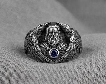 Anillo Raven Statement Ring de plata con piedra azul y banda gótica con diseño de pájaro.