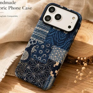Puede incluir: Funda de teléfono de tela hecha a mano con un diseño de patchwork en tonos azules y blancos. La funda presenta un diseño compatible con MagSafe y el texto "Handmade Fabric Phone Case". La funda está sobre una superficie de madera.