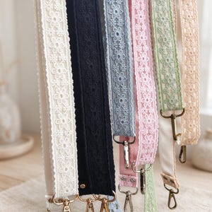 Può includere: Una collezione di sei tracolle in tessuto con un rivestimento in pizzo floreale. Le cinghie sono disponibili in crema, nero, azzurro, rosa, verde chiaro e beige, ciascuna dotata di moschettoni girevoli in metallo su entrambe le estremità.