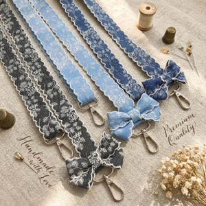 Puede incluir: Tres correas de tela en gris carbón, azul claro y azul medio, cada una con un patrón botánico blanco, bordes festoneados, un lazo decorativo y un mosquetón giratorio de metal plateado. El texto dice Handmade with Love y Premium Quality.