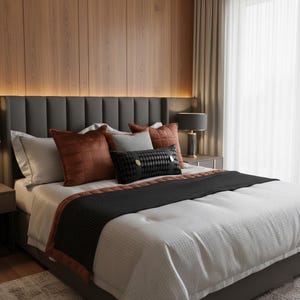 May include: A modern bedroom with a bed featuring a gray headboard and a white comforter. Decorative pillows in shades of rust, gray, and black add color. A black bed runner and wooden wall paneling complete the elegant design. A bedside lamp is visible.