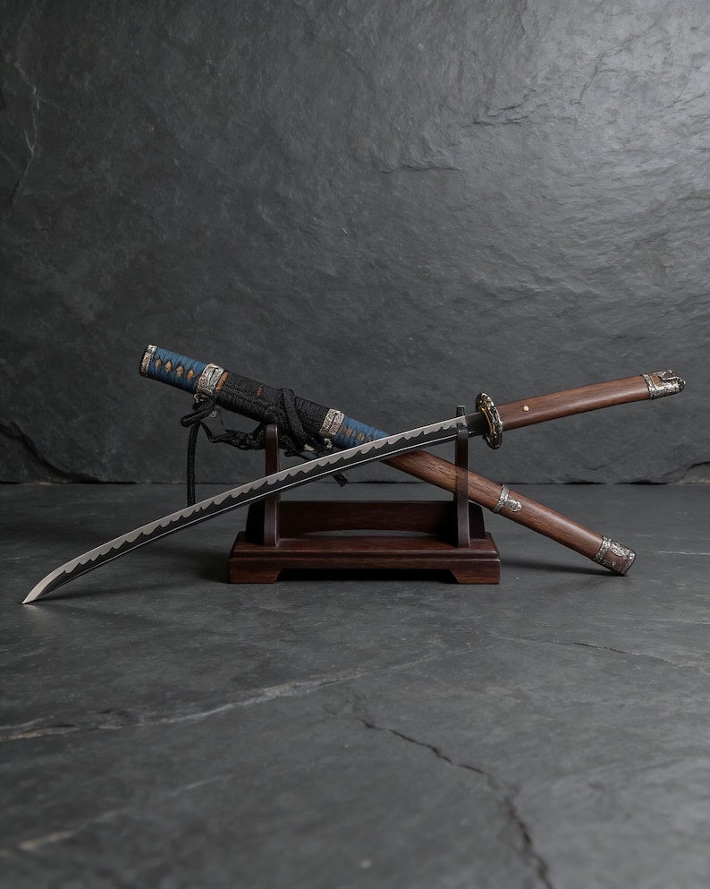 May include: A Japanese katana sword with a curved blade, displayed on a wooden stand. The hilt is wrapped in blue and black fabric, and the scabbard is visible. The sword's blade has a distinctive wavy edge.