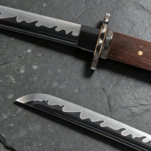 May include: Two Japanese swords with a wavy blade edge. The handles are made of dark wood and metal. The swords are shown on a dark, textured surface. The blades have a distinctive design.