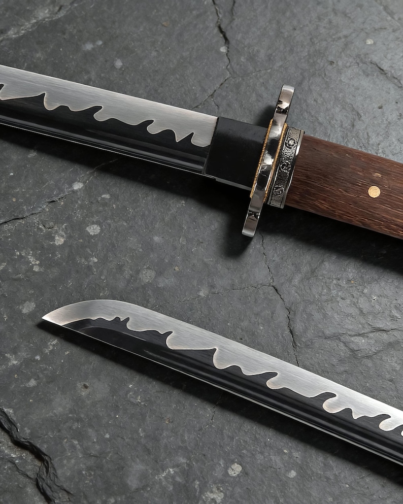 May include: Two Japanese swords with a wavy blade edge. The handles are made of dark wood and metal. The swords are shown on a dark, textured surface. The blades have a distinctive design.