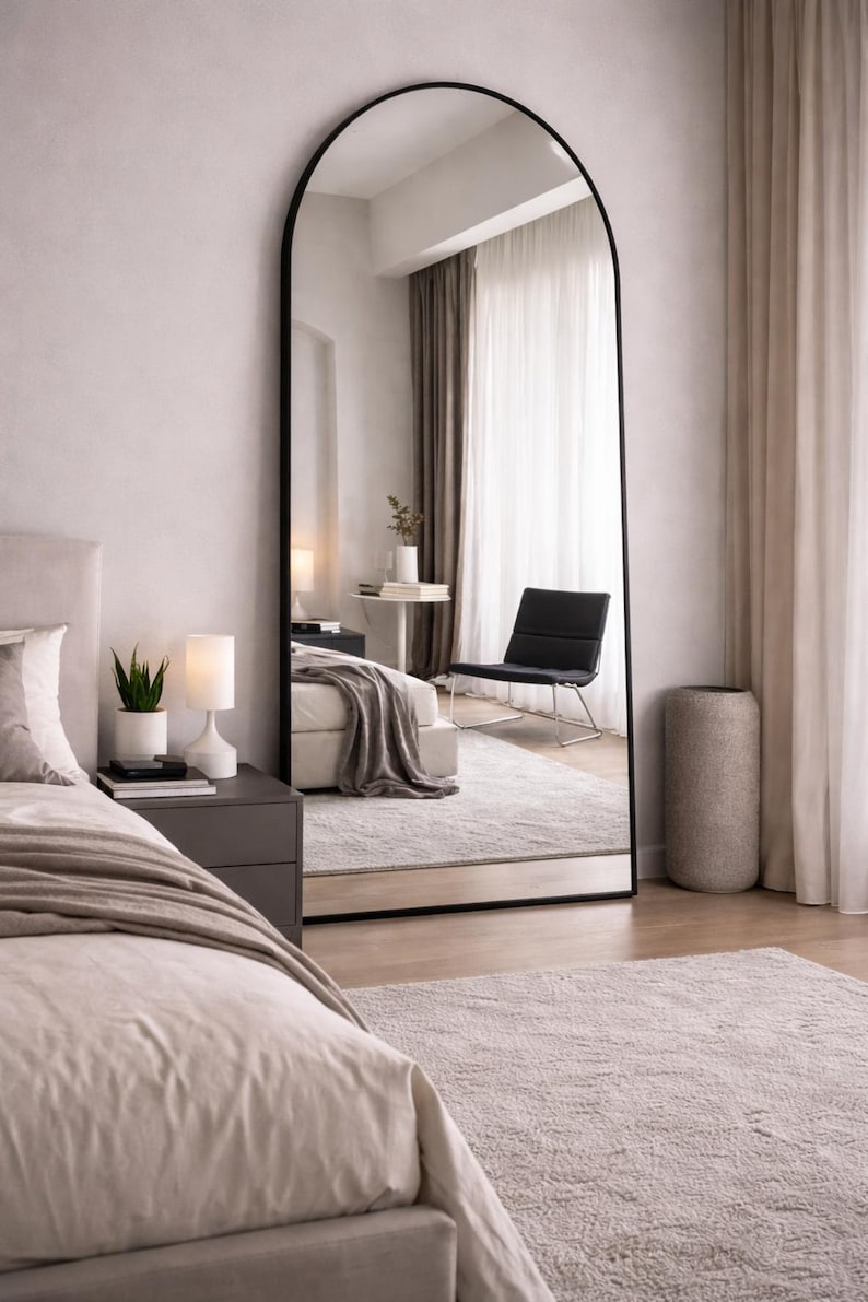 Black arched full length mirror in a minimalist bedroom