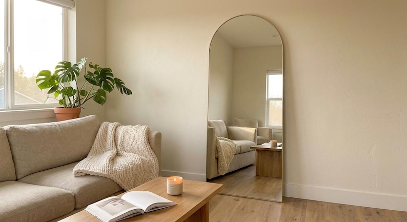 Gold arched full length floor mirror leaning in a cozy living room