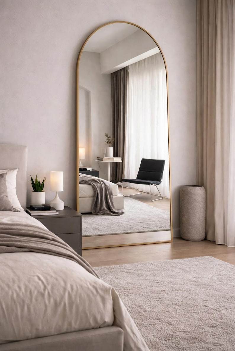 Gold arched floor mirror leaning in a bedroom