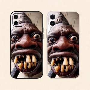 Pode incluir: Duas capas para smartphone com uma impressão gráfica em close-up de alto contraste de uma pessoa de pele escura, olhos arregalados e dentes proeminentes e irregulares. Uma capa tem borda preta, a outra tem um design de borda transparente.