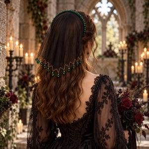 May include: A black veil headband featuring a band of small green beads and a sheer black fabric drape. The bottom edge of the veil is trimmed with a gold-toned zigzag wire accented with dangling green beads that catch the light.