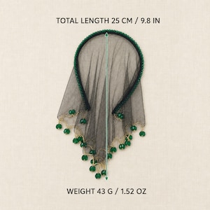 May include: A black headband with a sheer black veil featuring a scalloped edge adorned with small green beads. The item has a total length of 9.8 inches and a weight of 1.52 ounces. The text TOTAL LENGTH 25 CM / 9.8 IN and WEIGHT 43 G / 1.52 OZ is visible.